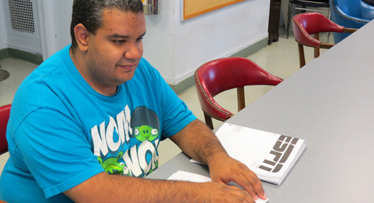 Emilio, a Helen Keller Services for the Blind client, reading braille
