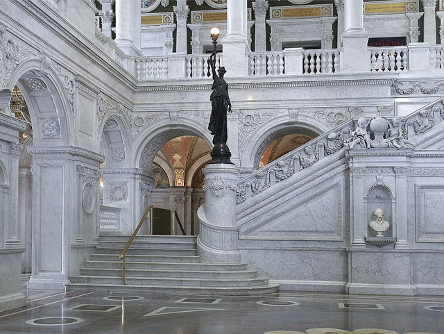 [Great Hall. View of grand staircase and bronze statue of female figure on newel post holding a torch of electric light, with bust of Thomas Jefferson at right. Library of Congress Thomas Jefferson Building, Washington, D.C.] (LOC)