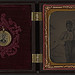 [Unidentified African American boy standing in front of painted backdrop showing American flag and tents ; campaign button with portraits of Lincoln on one side and Johnson on the opposite side are attached to inside cover of case] (LOC)
