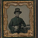 [Unidentified young soldier in Union uniform and plumed Hardee hat with plain gauntlets and revolver sitting next to table with books] (LOC)