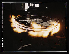 Retiring a locomotive driver wheel in the Atchison, Topeka, and Santa Fe railway locomotive shops, Shopton, near Fort Madison, Iowa. The tire is heated by means of gas until it can be slipped over the wheel. Contraction on cooling will hold it firmly in p