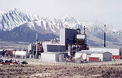 Photo: large, industrial building with steep, snow-capped mountain range in the background.