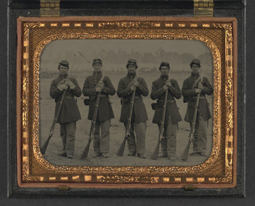 Five unidentified soldiers in Union uniform of the 6th Regiment Massachusetts Volunteer Militia outfitted with Enfield muskets in front of encampment
