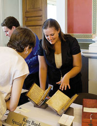 A woman pointing to a display of rare books.