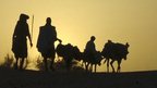 Tuareg family silhouetted with camels