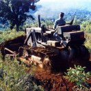 Photo: Ta-Ly, South Vietnam.  EOH2 James A. Brewer operates a bulldozer to clear land for a new missionary school, 7 April 1966.  He is also preparing to clear a small road through swamp land to gain access to rice paddies planned for planting.  Note M-14 rifle beside him.  Photographed by PH1 Tom Jaynes.   National Archives, 80-G-K-31102 (Color).