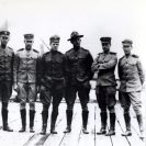 Photo: Commissioned Officers of the Aviation Corps, at the Naval Aeronautic Station, Pensacola, Florida, March 1914.  Present are (left to right):  Lieutenant V. D. Herbster, Lieutenant W.M. McIlvain, USMC; Lieutenant Junior Grade P.N.L. Bellinger, Lieutenant Junior Grade R. C. Saufley, Lieutenant J.H. Towers, Lieutenant Commander H. C. Mustin, Lieutenant B.L. Smith, USMC, Ensign G. DeC. Chavlier, and Ensign M.L. Stolz.   Courtesy of the Naval Historical Foundation, Collection of Captain H.C. Richardson.   NHHC Photograph Collection, NH 95633.
