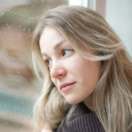 Woman looking through rain speckled window