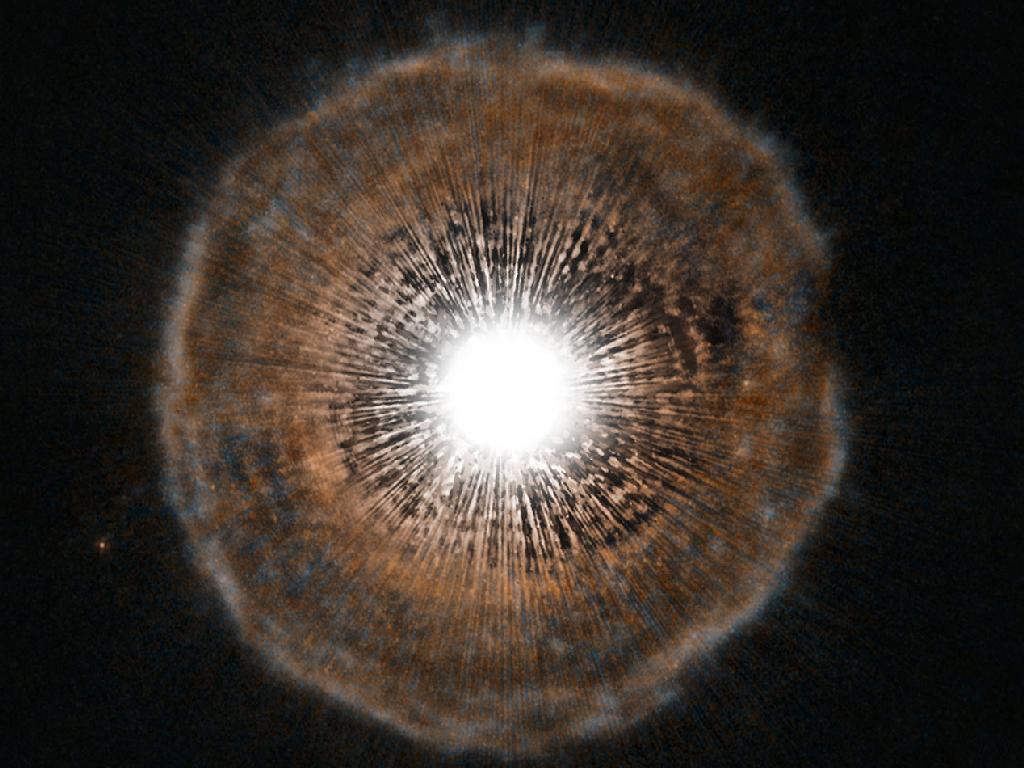Image description: Camelopardalis, or U Cam for short, is a star nearing the end of its life. As stars run low on fuel, they become unstable. Every few thousand years, U Cam coughs out a nearly spherical shell of gas as a layer of helium around its core begins to fuse. The gas ejected in the star’s latest eruption is clearly visible in this picture as a faint bubble of gas surrounding the star.
Image from ESA/NASA