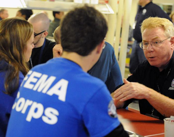 Federal Coordinating Officer Michael Byrne, right, talks to FEMA Corps members aboard the Training Ship Empire State VI, docked on the East River at the foot of the Throgs Neck Bridge.