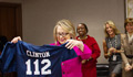Secretary Clinton holds up a football jersey with the number 112, representing the number of countries she has visited while in office.
