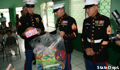 three marines in their uniforms standing in a large room, one of them carries a large plastic bag full of wrapped gifts
