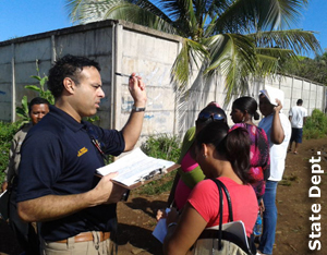 Instructor and students talking in an open space by a concrete wall