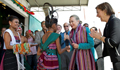 U.S. Secretary of State Hillary Clinton, accompanied by U.S. Ambassador to Timor-Leste, Judith R. Fergin, is greeted by traditional dancers at the Cooperativa Cafe Timor in Dili, Timor-Leste