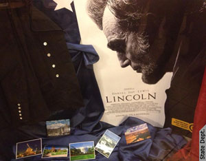 A Lincoln című film plakátja Lincoln portréjával, az előtérben katonai egyenruha és amerikai tájakat ábrázoló képeslapok (Követségi fotó: Tenk Anita)