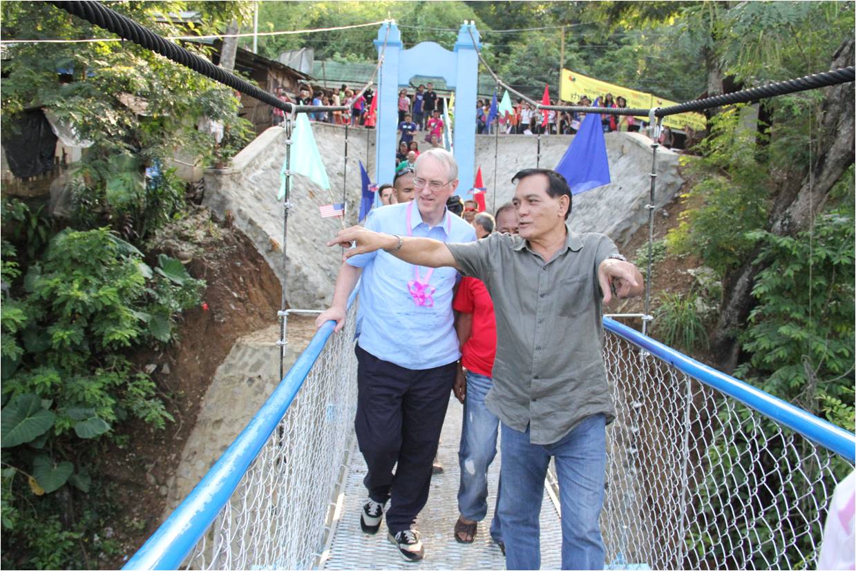 U.S. Deputy Chief of Mission Brian L. Goldbeck (left) and Zamboanga City Mayor Celso Lobregat cross a new suspension footbridge built in Barangay Pasonanca through a partnership between the U.S. Agency for International Development (USAID) and the city government.