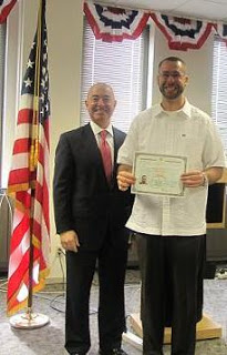 Erick Lopez, right, receives the first new Certificate of Naturalization from Director Mayorkas in Baltimore