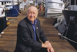 portrait of Lee Alverson sitting on a dock with ships in background