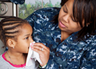 A mother helping her young daughter blow her nose