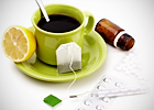 A cup of tea with a slice of lemon and medicine next to it