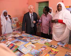 Two men talking as two women look on at a table of children's books. (Photo Credit: State Department)