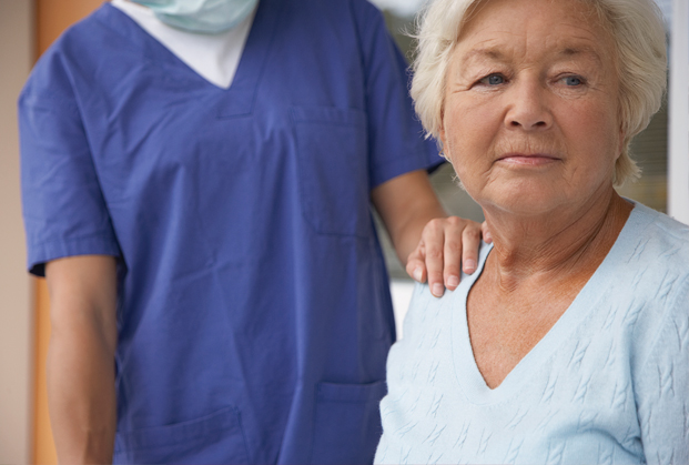Elderly female patient with health care provider's hand on shoulder
