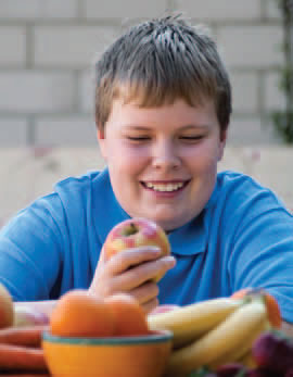 Smiling boy eating an apple.