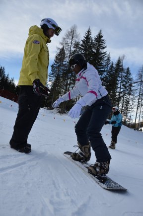 (Left) Chris Wolff, Vicenza Outdoor Recreation snowboard instructor, helps a student learn how to board down a hill.