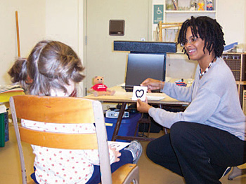 Lady playing an eye card game with a young kid.