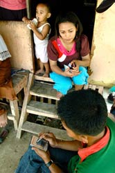 Photo courtesy of DataDyne.org, man seated enters data on a handheld device, woman faces him sitting on wooden steps in doorway
