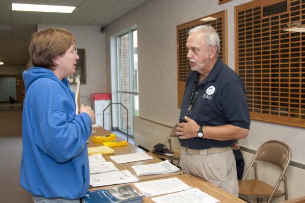 A FEMA community relations specialist talks to a displaced resident after a town hall meeting.