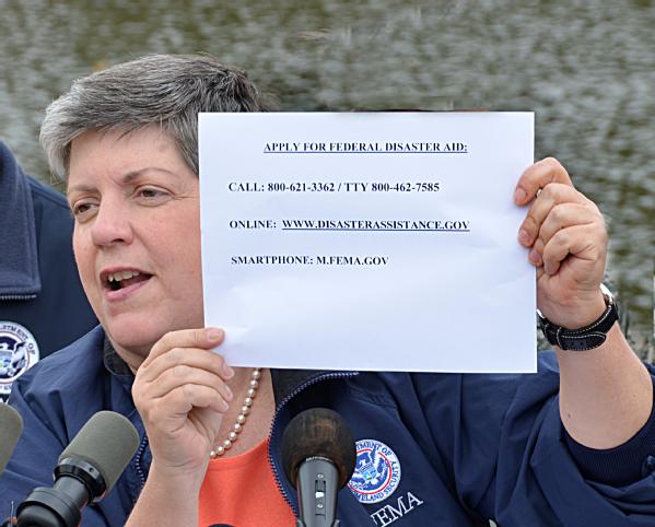 Minot, ND, July 13, 2011 -- Secretary Janet Napolitano speaks to the media and holds up a sign with the FEMA registration information. She strongly urged affected residents in eligible counties to apply for assistance.