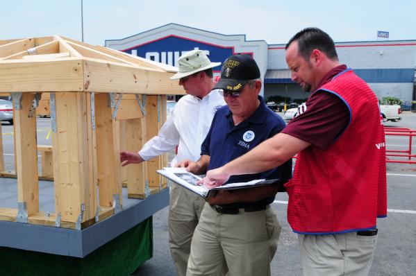 A FEMA mitigation specialist and Lowe's Store Manager review the plans for a ' DAWG HAUS' demonstration, which is a building method that helps structures withstand high winds.