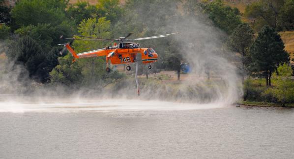 Firefighting helicopter hovering over a lake.