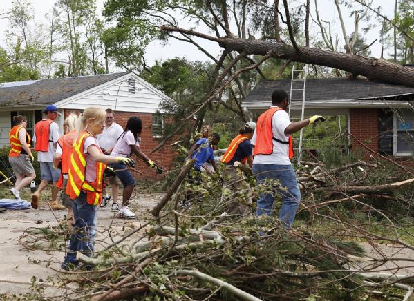Volunteers assist a homeowner clean up branches after a tornado near Raleigh, North Carolina. 