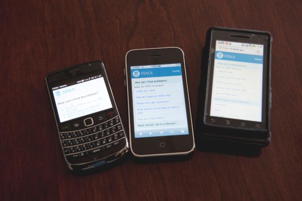 Mobile phones set on a table displaying the FEMA mobile site homepage.