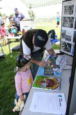 A FEMA staff member helps a child learn about disaster preparedness.