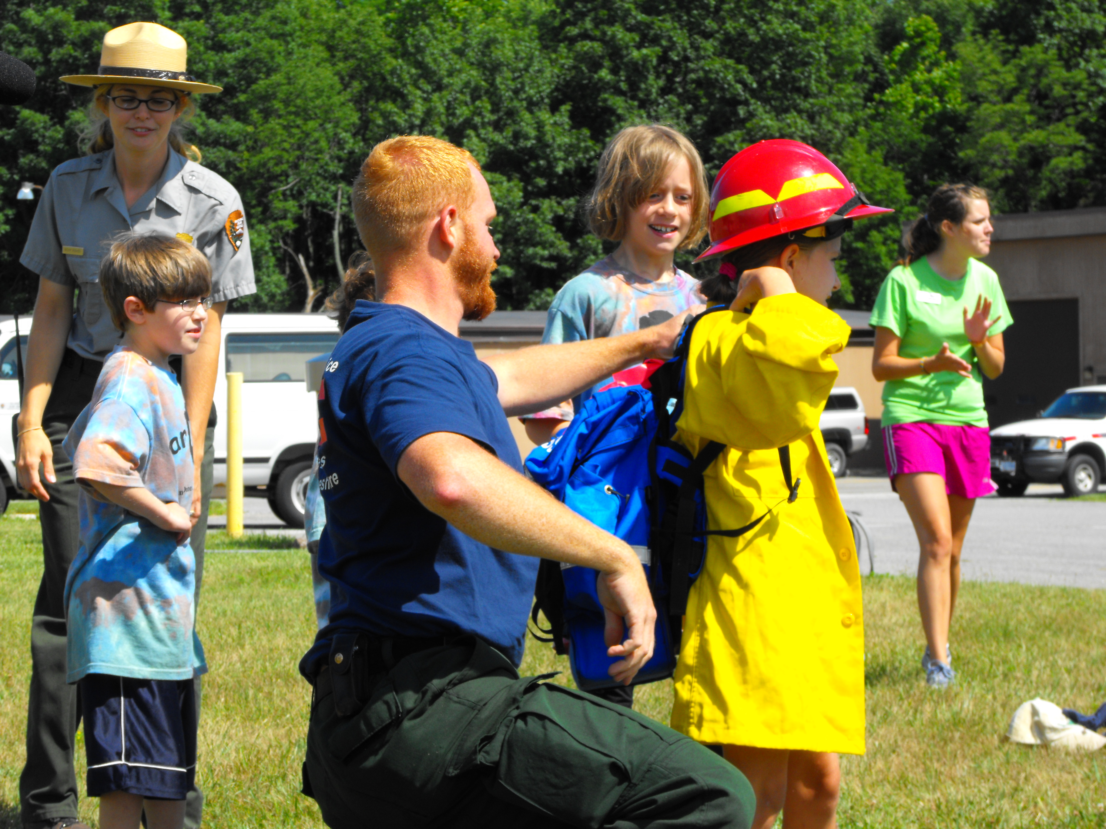 A firefighter helps a child put on a fire suit during a fire education class.