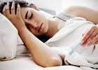 Mujer enferma en cama tomándose la temperatura