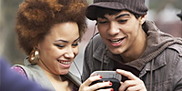 Male and female teens listening to music outside