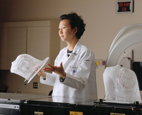 Photo of a female attendant holding lattice face mask for positioning patient for radiation therapy