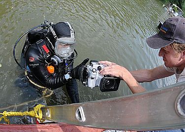 Underwater archeologist Alexis Catsambis prepares to dive as fellow archeologist George Schwarz hands him an underwater video camera. Both archeologists, assigned to Naval History and Heritage Command, are conducting the excavation of the U.S. sloop-of-war Scorpion. The ship was scuttled in the Patuxtent River to avoid capture by British forces during the War of 1812.  U.S. Navy photo by Mass Communication Specialist 2nd Class Kenneth G. Takada (Released)  100806-N-9671T-023