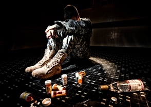 Service member surrounded by medications and an empty bottle