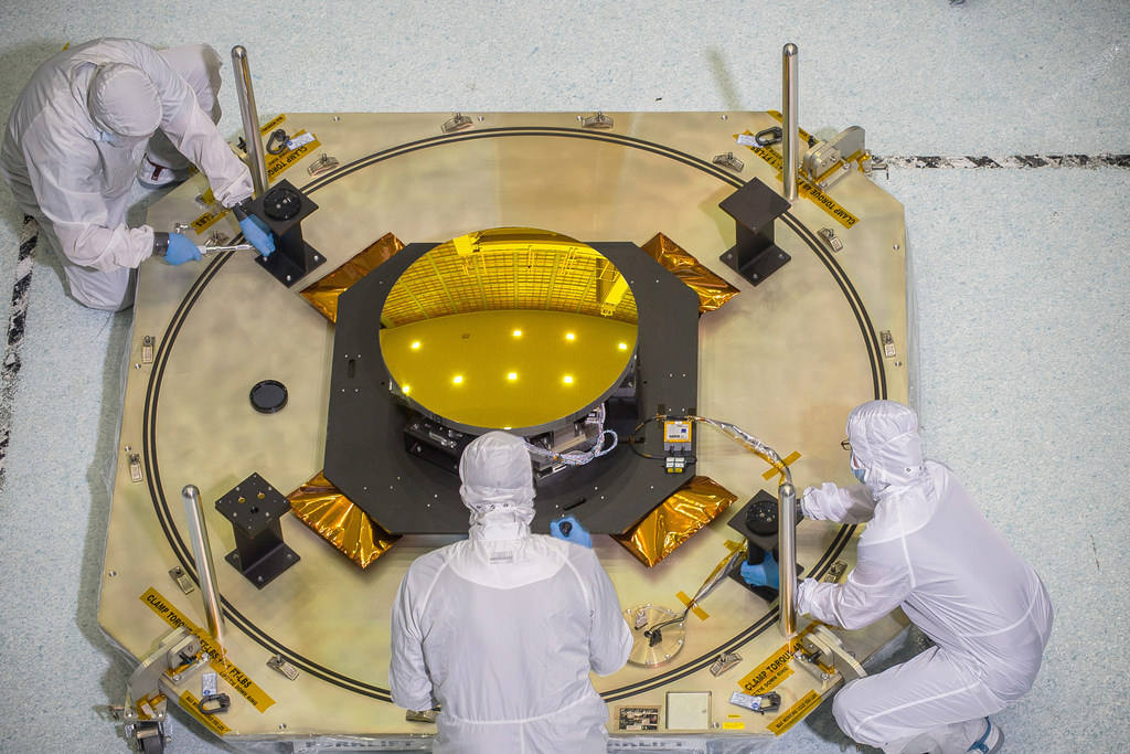 Image description: This round, gold coated secondary mirror that looks like a sun will fly aboard NASA&#8217;s James Webb Space Telescope. The thickness of the gold coating on the mirrors is only 100 nanometers thick. A human hair is roughly 1,000 times thicker.
Photo by Chris Gunn, NASA.