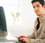 An adult male typing on a 

computer.