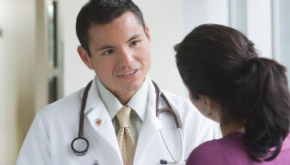 Imagen de un doctor hablando con una mujer en el pasillo de un hospital.