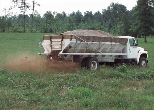 Large truck rolling through cropfield, dispensing nutrients from the back.