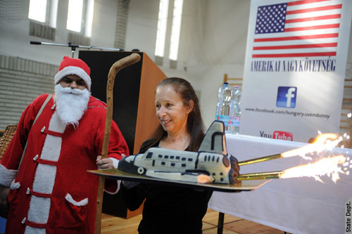 Marsha Ivins holds the cake as 'Santa Claus' looks on. (Embassy photo)
