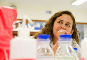 Woman researcher in lab, various bottles and containers in foreground