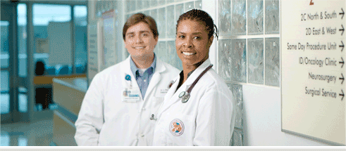 Two smiling medical professionals in the corridor of a hospital.